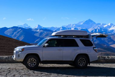 Tibet, Çin 'de yüksek rakımlı dağın tepesinde çatısı olan beyaz bir off-road arabası.