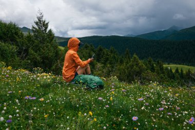 Yürüyüş yapan kadın yüksek irtifa orman zirvesinde fotoğraf çekmek için akıllı telefon kullanıyor.