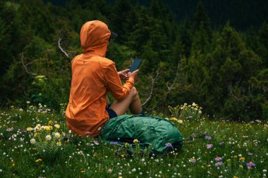 Yürüyüş yapan kadın yüksek irtifa orman zirvesinde fotoğraf çekmek için akıllı telefon kullanıyor.