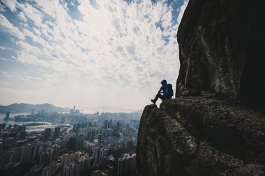 Uçurumun kenarında oturan kadın Hong Kong 'un güzel manzarasının tadını çıkar.