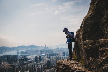 Kadın Hong Kong 'u görmek için dağ yamacına tırmanıyor.