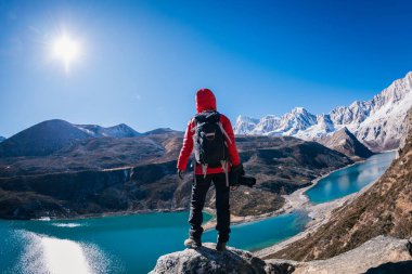 Sırt çantalı kadın fotoğrafçı yüksek irtifada dağın tepesinde uçurumun kenarında