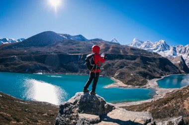 Sırt çantalı kadın fotoğrafçı yüksek irtifada dağın tepesinde uçurumun kenarında