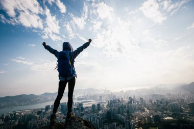 Başarılı kadın yürüyüşçü uçurumun kenarında duruyor kollarını uzatarak güzel Hong Kong 'a doğru.