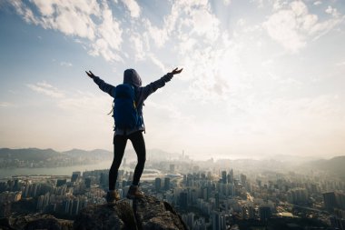 Başarılı kadın yürüyüşçü uçurumun kenarında duruyor kollarını uzatarak güzel Hong Kong 'a doğru.
