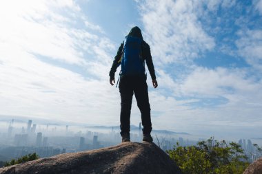 Kadın yürüyüşçü dağın tepesinde duruyor Hong Kong ve Shenzhen Ctiy 'in güzel manzarasına bakıyor.