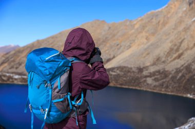 Yükseklik dağının tepesinde sırt çantalı kadın fotoğrafçı.