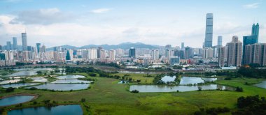 Hong Kong ve Shenzhen siluetleri üzerinde balık havuzları ile kırsal yeşil alanların havadan görünümü