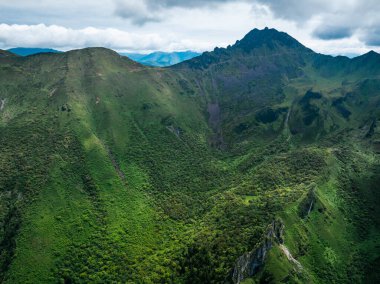 Bulutlu gökyüzünün altında yemyeşil dağlar