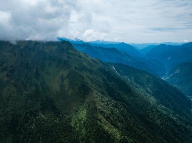 Bulutlu gökyüzünün altında yemyeşil dağlar