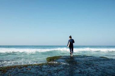 Sörf tahtası olan kadın sörf yapmaya deniz kenarına gidiyor. 