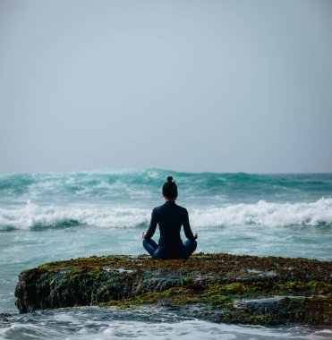 Yaklaşan güçlü deniz dalgaları bakan sahil uçurum kenarında Yoga kadın meditasyon