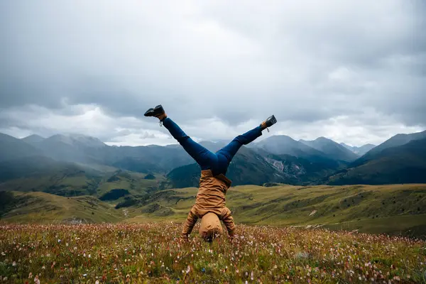 Yüksek rakımlı dağ otlaklarında amuda kalkan bir kadın yürüyüşçü. 