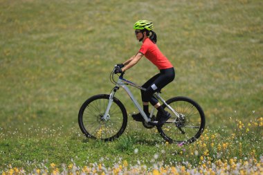 Dağın tepesinde dağ bisikleti süren Asyalı bir kadın. 