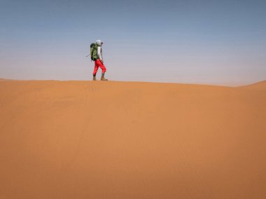 Çölde sırt çantası taşıyan bir kadın.