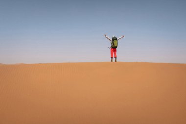 Çölde sırt çantası taşıyan bir kadın.