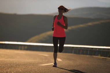 Gün batımında dağ yolunda koşan kadın koşucu 