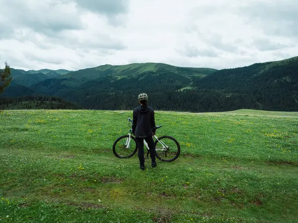 Çiçekli çayır dağ patikasında dağ bisikleti süren kadının hava manzarası. 