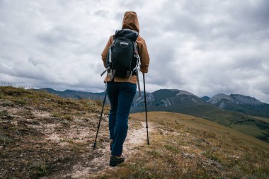 Sırt çantalı bir kadın yüksek irtifada dağ yürüyüşü yapıyor. 