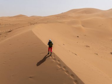 Sırt çantalı bir kadın çölde yürüyüş yapıyor.
