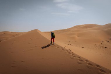 Sırt çantalı bir kadın çölde yürüyüş yapıyor.