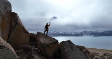 Dağlarda, göl kenarında elini kaldırmış bir kadın yürüyüşçü, doğa.