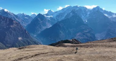 Sırt çantalı bir kadın yüksek rakımlı dağlarda dik yamaçlara tırmanıyor.