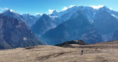 Sırt çantalı bir kadın yüksek rakımlı dağlarda dik yamaçlara tırmanıyor.