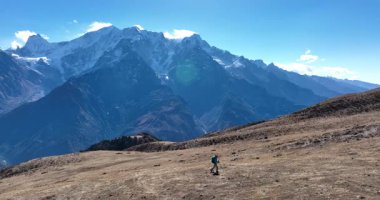 Sırt çantalı bir kadın yüksek rakımlı dağlarda dik yamaçlara tırmanıyor.