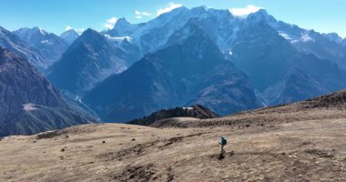 Sırt çantalı bir kadın yüksek rakımlı dağlarda dik yamaçlara tırmanıyor.