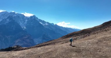 Sırt çantalı bir kadın yüksek rakımlı dağlarda dik yamaçlara tırmanıyor.
