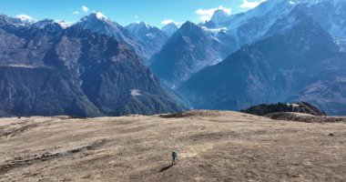 Sırt çantalı bir kadın yüksek rakımlı dağlarda dik yamaçlara tırmanıyor.