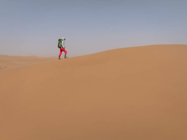 Sırt çantalı bir kadın çölde yürüyüş yapıyor.