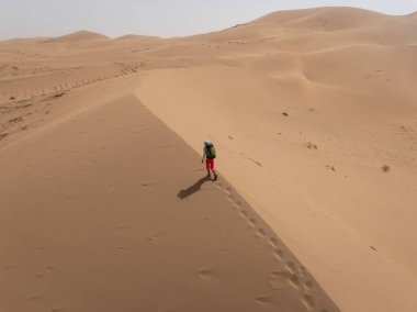 Sırt çantalı bir kadın çölde yürüyüş yapıyor.