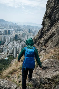 Hong Kong manzarasını görmek için uçurumun kenarında yürüyüş yapan bir kadın.