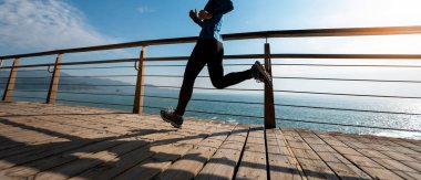 Sahil sahil gündoğumu sırasında sportif kadın koşucu sabah egzersiz