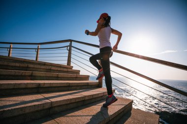 Sahil sahil gündoğumu sırasında sportif kadın koşucu sabah egzersiz
