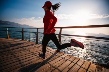 Sahil sahil gündoğumu sırasında sportif kadın koşucu sabah egzersiz
