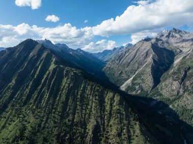 Koyu yeşil bir vadi ve etrafındaki dağların yüksek açılı görüntüsü..