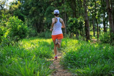 Woman trail runner running at tropical forest mountain peak