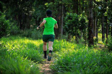 Woman trail runner running at tropical forest mountain peak