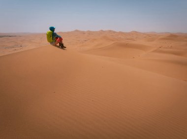 Sırt çantalı bir kadın çölde yürüyüş yapıyor.