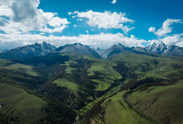 Вид с воздуха на красивые высокогорные снежные шапки и ландшафт лесных лугов в Китае