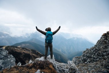 Başarılı sırt çantalı, Tibet 'teki kar kaplı dağlara bakan dağın tepesindeki manzaranın keyfini çıkar.