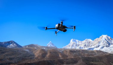 İHA yüksek irtifada, dağın tepesinde uçuyor.