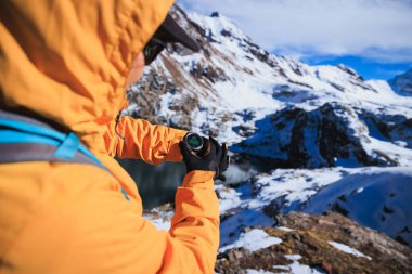 Sırt çantalı bir kadın yüksek irtifadaki dağ tepesindeki spor nöbetlerinde yüksekliği kontrol ediyor.
