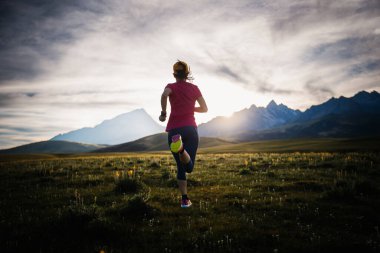Yüksek rakımlı çayırlarda koşan sportif bir kadın.
