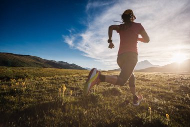 Sportif, koşucu bir kadın dağlarda koşuyor. 
