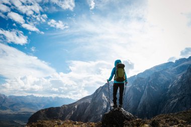 Sırt çantalı bir kadın yüksek rakımlı dağlarda dik yamaçlara tırmanıyor.