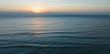 soft-focus image of a sunset over the ocean, with a golden reflection on the water surface